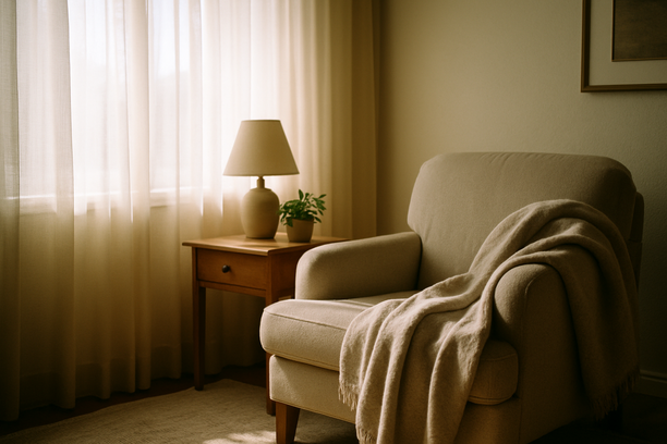 alt_text: A serene living room corner with a cozy chair and blanket, bathed in soft, natural light.