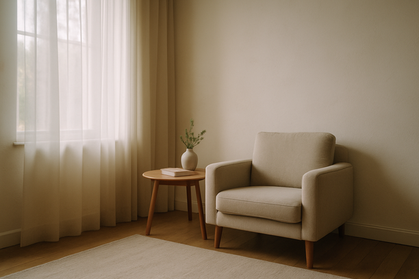 alt_text: Serene living room corner bathed in soft morning light, featuring minimal furniture and sheer curtains.
